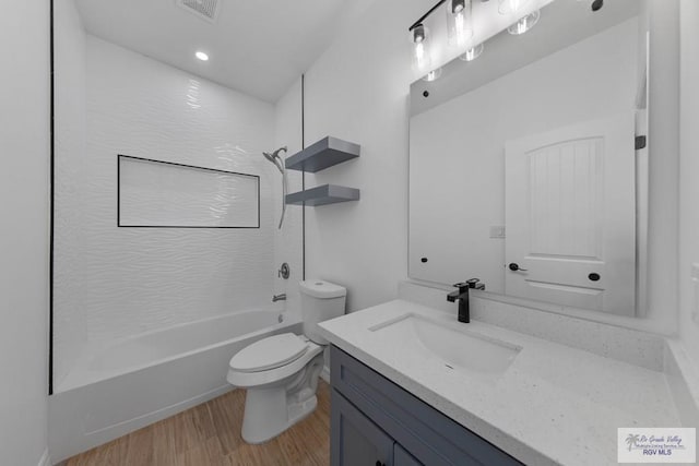 full bathroom featuring hardwood / wood-style floors, vanity, toilet, and tiled shower / bath