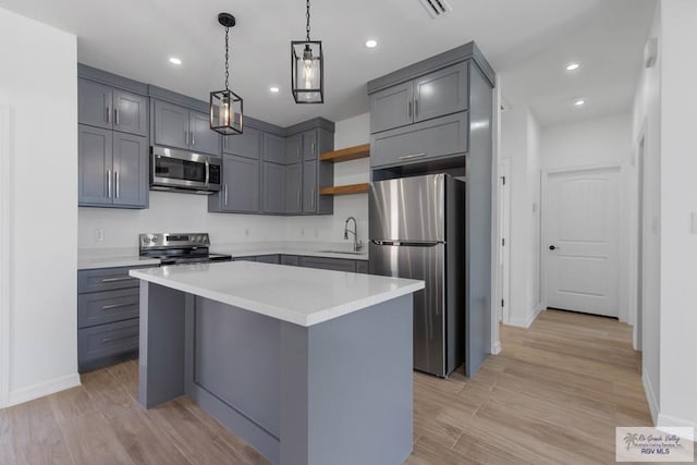 kitchen with appliances with stainless steel finishes, a center island, gray cabinetry, and sink