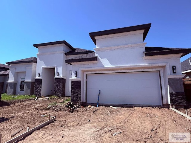 9608 Lake Concordia Ct, Los Fresnos, TX 78566 - view of front of home with dirt driveway, stone siding, an attached garage, and stucco siding