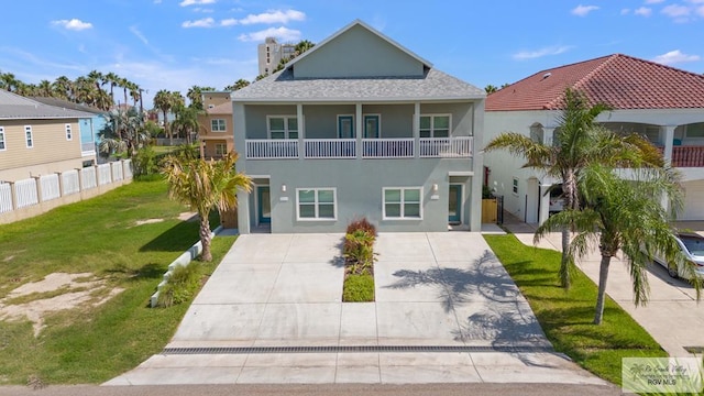 213B W Cora Lee Dr Unit B, South Padre Island, TX 78597 - view of front of home with stucco siding, a chimney, concrete driveway, and a balcony