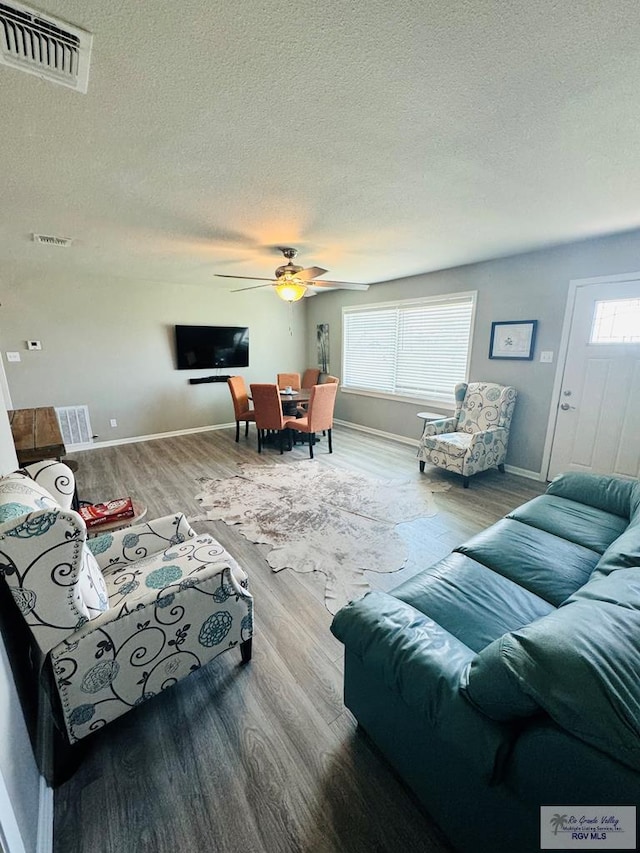 living room with hardwood / wood-style floors, ceiling fan, a healthy amount of sunlight, and a textured ceiling