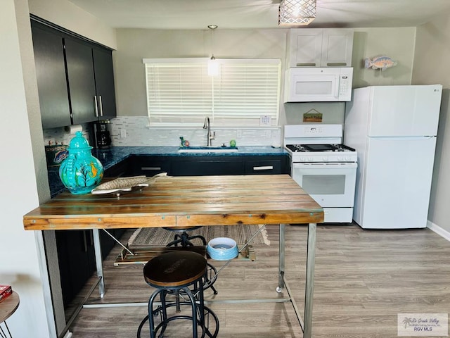 kitchen featuring pendant lighting, white appliances, sink, light hardwood / wood-style flooring, and decorative backsplash