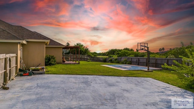 patio terrace at dusk featuring a lawn