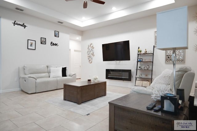 tiled living room featuring a tray ceiling and ceiling fan