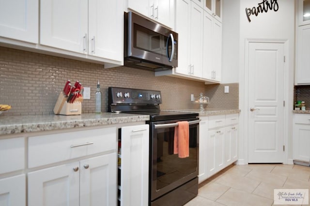 kitchen featuring backsplash, electric range, light tile patterned floors, light stone counters, and white cabinetry