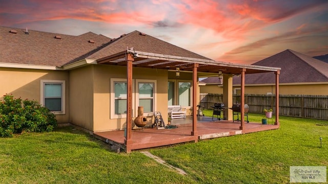 back house at dusk featuring a deck and a yard