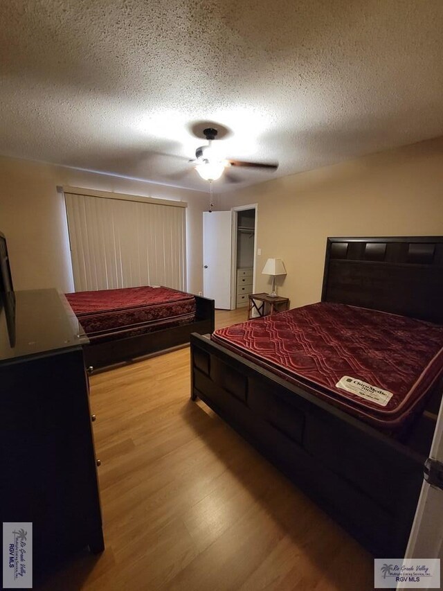 bedroom with ceiling fan, wood-type flooring, and a textured ceiling