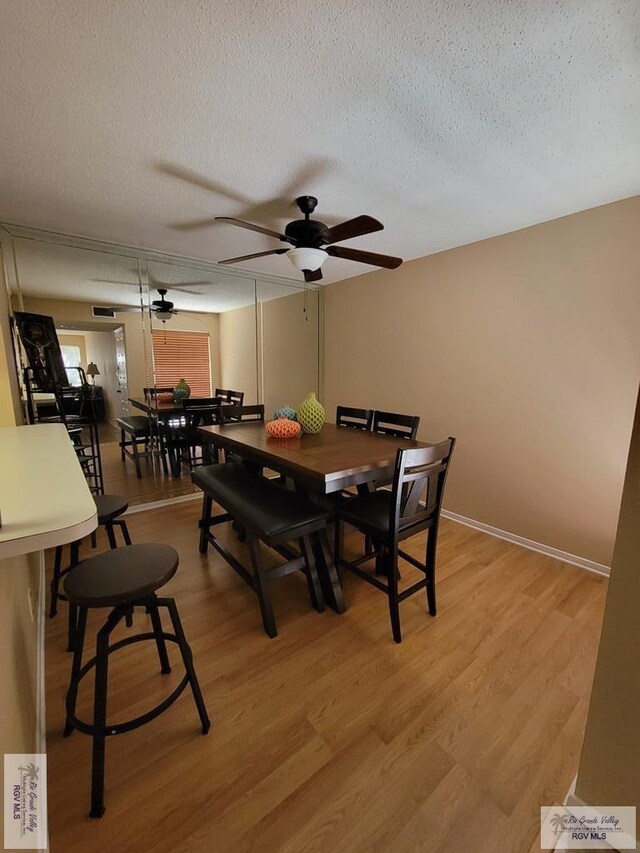 dining space featuring ceiling fan, a textured ceiling, and light hardwood / wood-style flooring