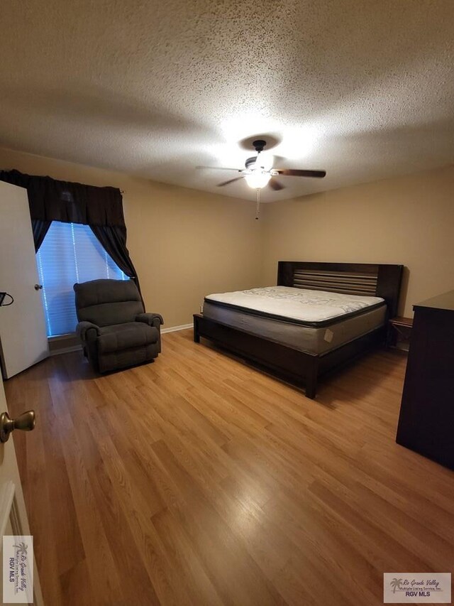 unfurnished bedroom with ceiling fan, wood-type flooring, and a textured ceiling