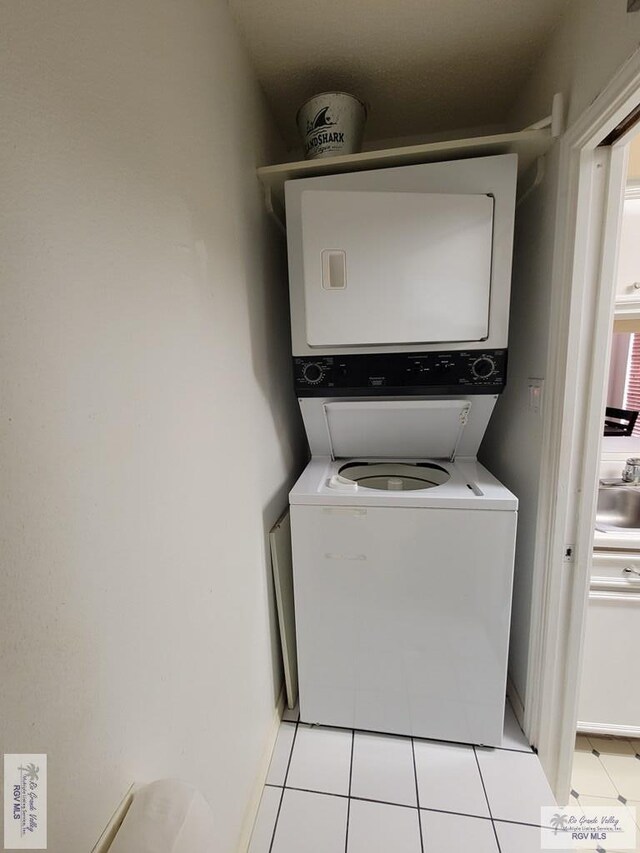 laundry room featuring stacked washer / drying machine and light tile patterned floors