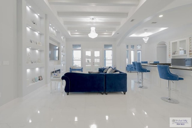 living room featuring french doors, a tray ceiling, and beam ceiling