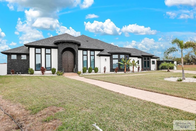 view of front of property featuring stone siding, roof with shingles, and a front lawn