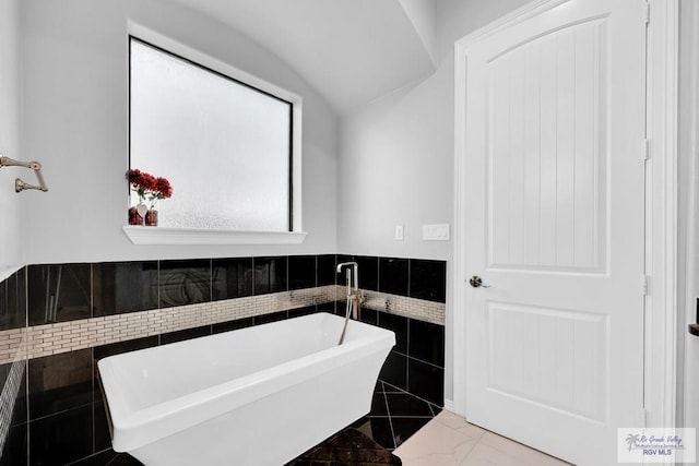 bathroom with a bathtub and tile walls