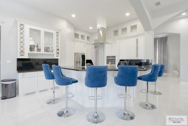 kitchen with backsplash, white cabinetry, a kitchen bar, and stainless steel appliances