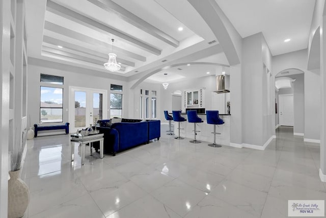 living room featuring a tray ceiling and french doors