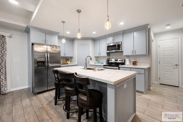 4438 Mckenzie Rd, Brownsville, TX 78521 - kitchen with appliances with stainless steel finishes, gray cabinetry, wood tiled floors, light countertops, and an island with sink
