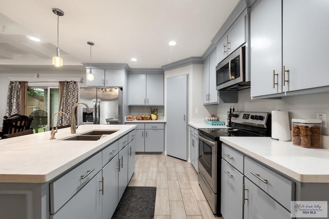 4438 Mckenzie Rd, Brownsville, TX 78521 - kitchen featuring appliances with stainless steel finishes, gray cabinets, light countertops, decorative light fixtures, and a center island with sink