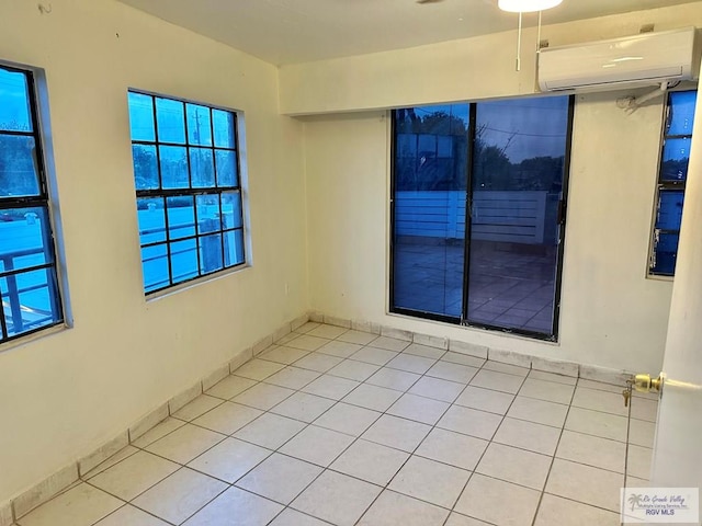 empty room with light tile patterned floors, a wall mounted AC, a healthy amount of sunlight, and ceiling fan