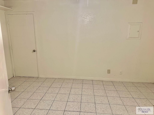 empty room with light tile patterned floors and electric panel