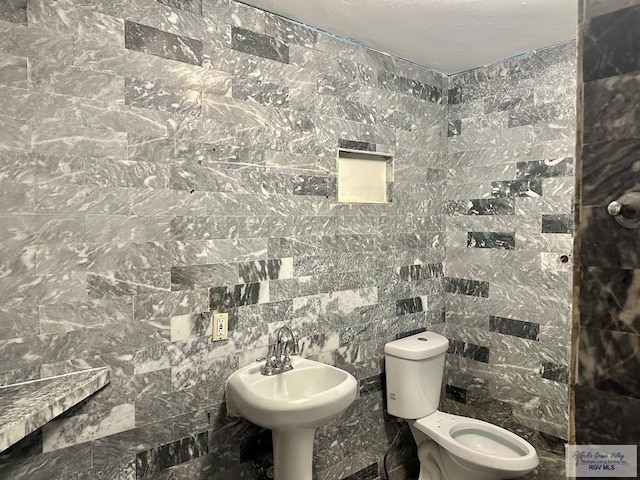 bathroom featuring sink, toilet, and tile walls