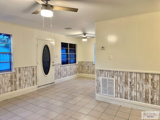 interior space with ceiling fan and wooden walls