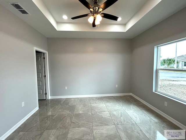 empty room featuring a raised ceiling and ceiling fan