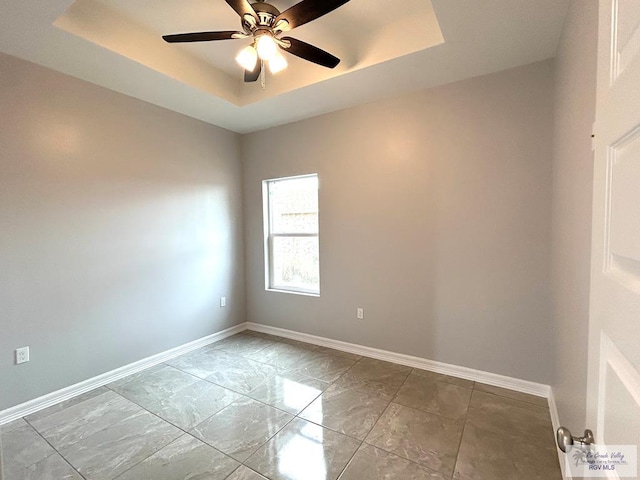 empty room with a raised ceiling and ceiling fan