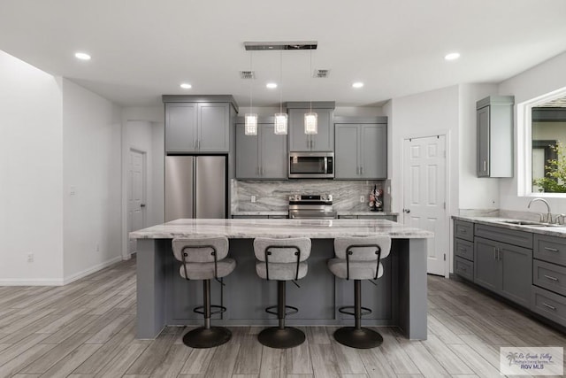 kitchen with appliances with stainless steel finishes, a sink, and gray cabinetry