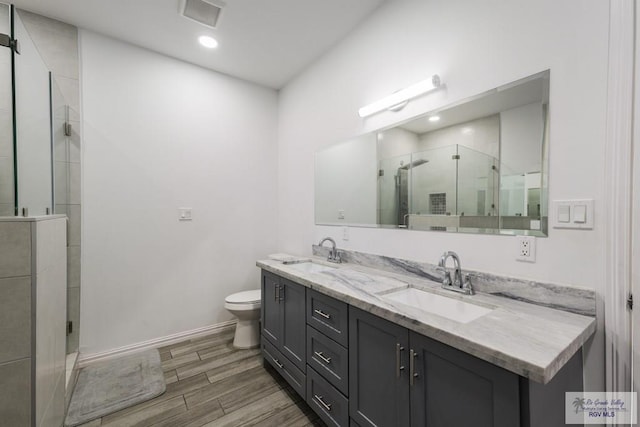 bathroom featuring a shower stall, double vanity, a sink, and wood tiled floor