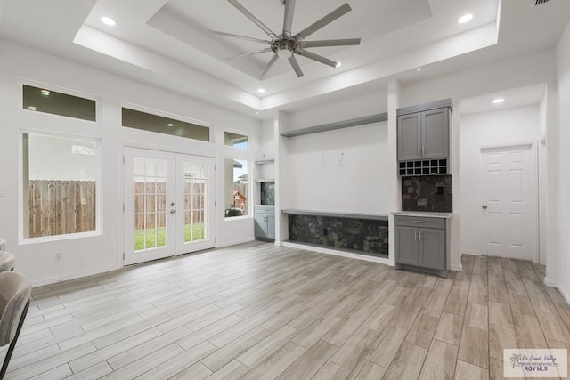 interior space with recessed lighting, a ceiling fan, french doors, light wood-type flooring, and a raised ceiling