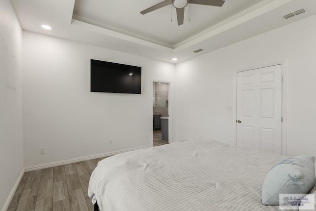 bedroom with recessed lighting, wood finished floors, visible vents, baseboards, and a tray ceiling