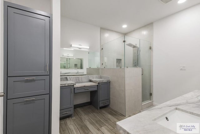 bathroom with wood finish floors, a shower stall, vanity, and recessed lighting