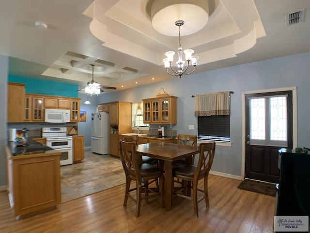 dining space with a raised ceiling, hardwood / wood-style floors, and coffered ceiling