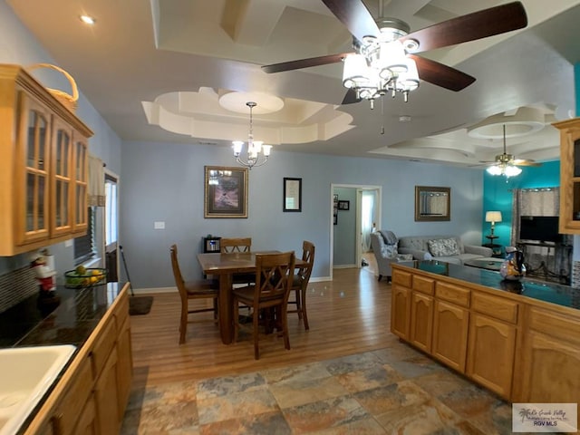 kitchen featuring a tray ceiling, sink, pendant lighting, and light hardwood / wood-style flooring