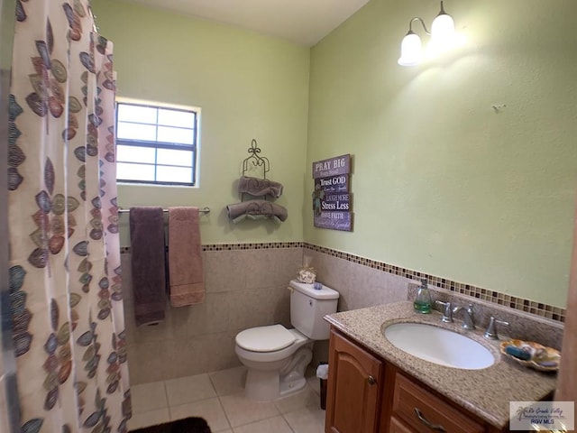 bathroom with vanity, a shower with curtain, tile patterned flooring, toilet, and tile walls