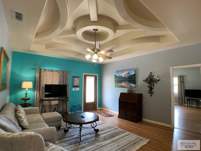 living room featuring a raised ceiling, ceiling fan, and wood-type flooring