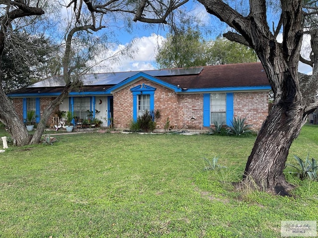 ranch-style home featuring solar panels and a front lawn