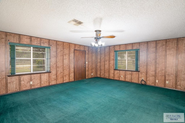 19863 Tilden Rd, San Benito, TX 78586 - unfurnished room featuring carpet, wooden walls, ceiling fan, and a textured ceiling