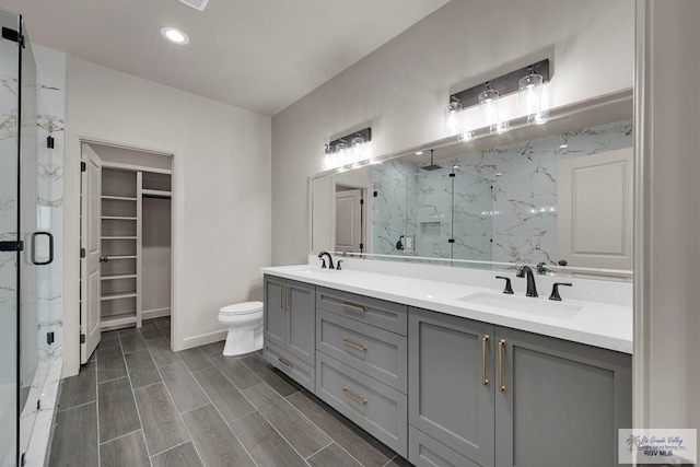 full bathroom with a sink, a marble finish shower, wood finish floors, and a walk in closet