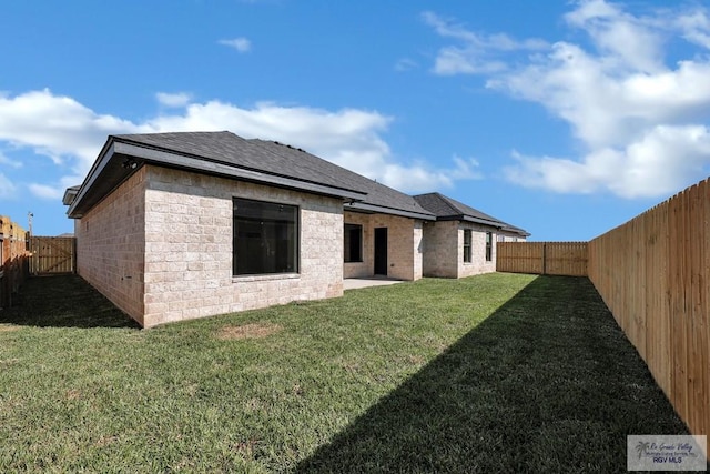 back of property featuring a patio, a yard, a fenced backyard, and a shingled roof