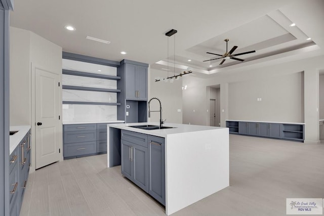 kitchen with a sink, light countertops, a tray ceiling, and open shelves