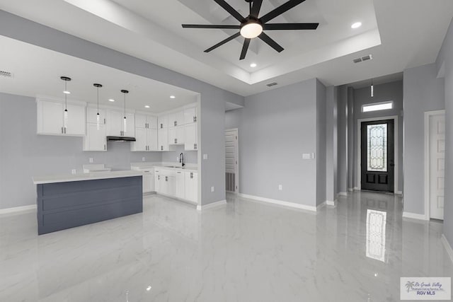 kitchen featuring a tray ceiling, visible vents, and baseboards