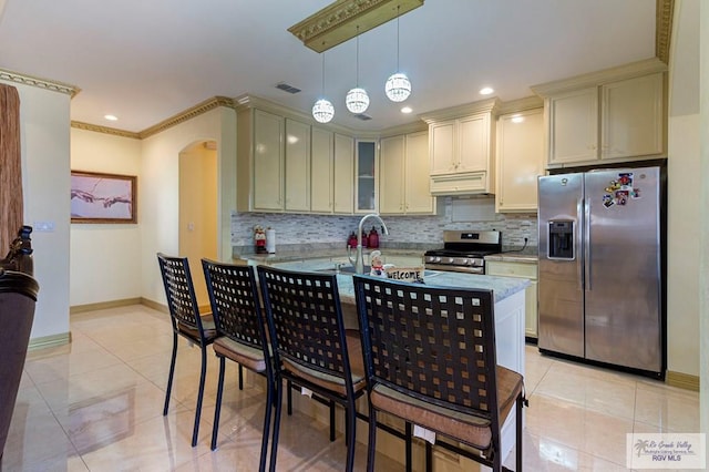 kitchen with ventilation hood, hanging light fixtures, light tile patterned floors, ornamental molding, and stainless steel appliances