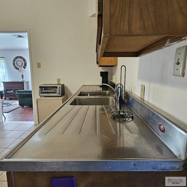 kitchen featuring tile patterned floors, a sink, visible vents, and a toaster