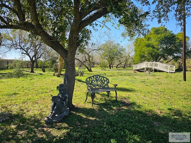 view of property's community with a lawn, a deck, and fence