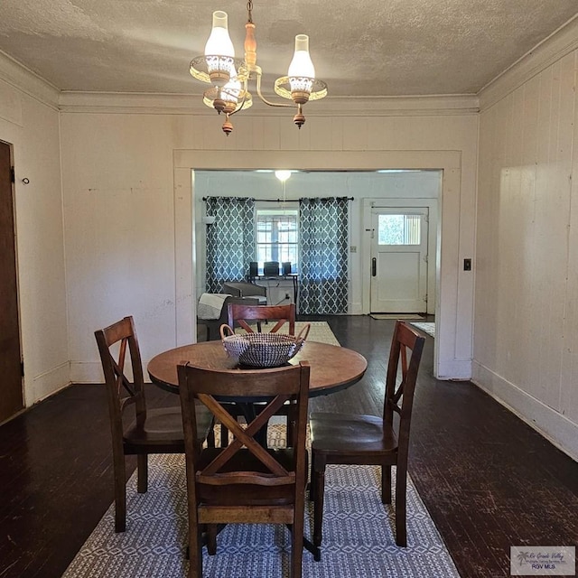 dining area with a textured ceiling, ornamental molding, and dark wood-type flooring