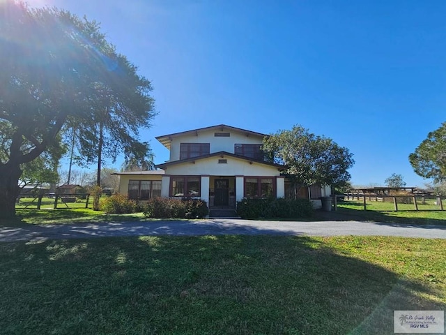 view of front of house featuring driveway, a front yard, and fence