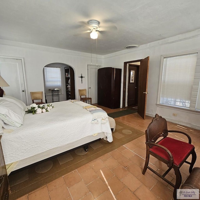 bedroom featuring a ceiling fan, arched walkways, and visible vents