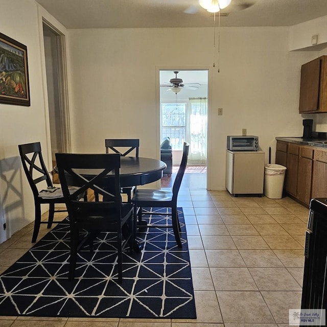 dining room featuring light tile patterned flooring, a ceiling fan, and a toaster