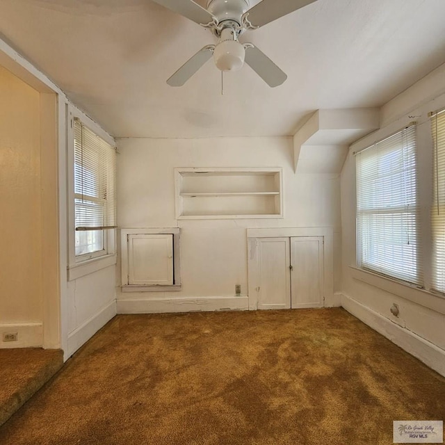 unfurnished room featuring a ceiling fan, carpet, a wealth of natural light, and built in features